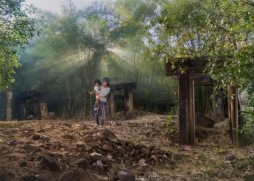 Tourists capturing candid portraits of a Khmer family amidst hidden, overgrown ancient ruins on an off-the-beaten-path Angkor photography excursion.